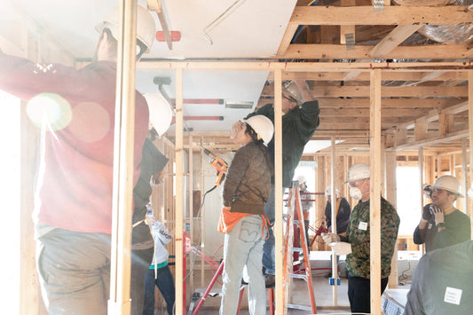 Volunteers helping put up the frame of a building