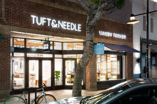 Glendale California Tuft and Needle store front at night sitting next to Warby Parker