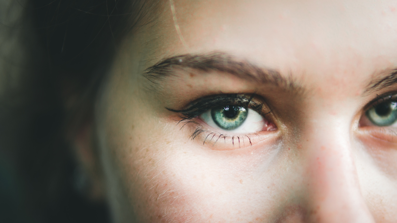 Green eyes of a female looking into a camera