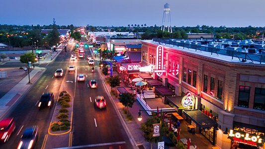 Arial photo of downtown Gilbert, AZ at night with cars on the streets and all the restaurants & business signs lit up