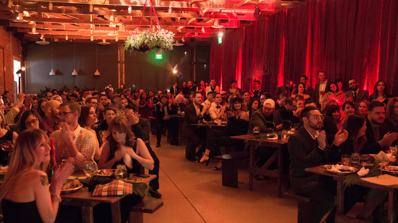Photo of people sitting down at tables dressed up in 1920s outfits watching a show