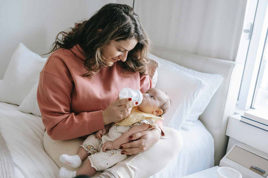 Picture of a mom feeding her a baby a bottle in bed