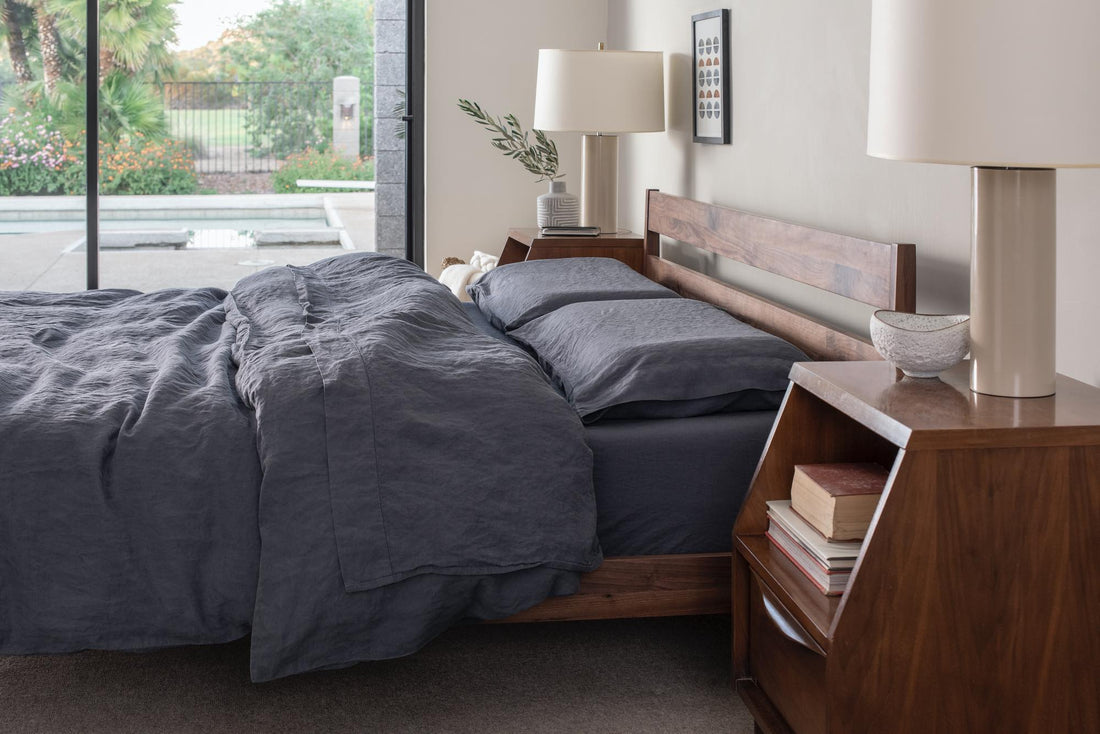 Tuft and Needle wood bed frame and mattress in a bedroom with a big sliding glass door