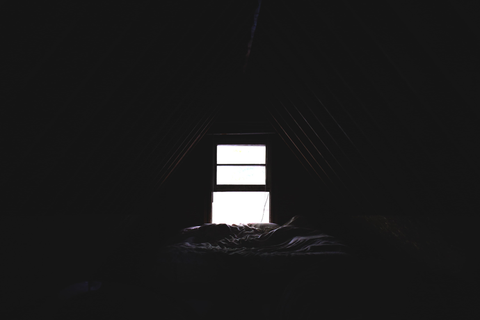 Dark room with an undressed window open and a bed in front of it