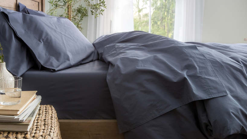 Bed made with pillows and a comforter folded down. All bedding is blue.