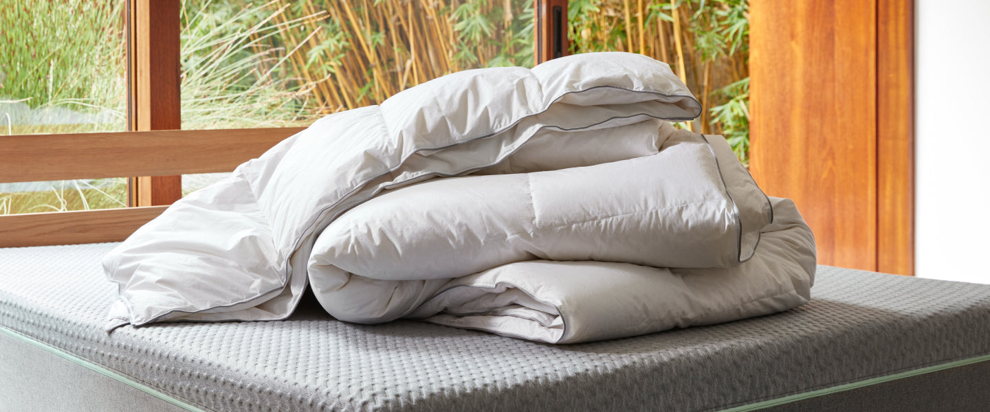 White duvet inserts placed upon a grey mattress placed in front of window