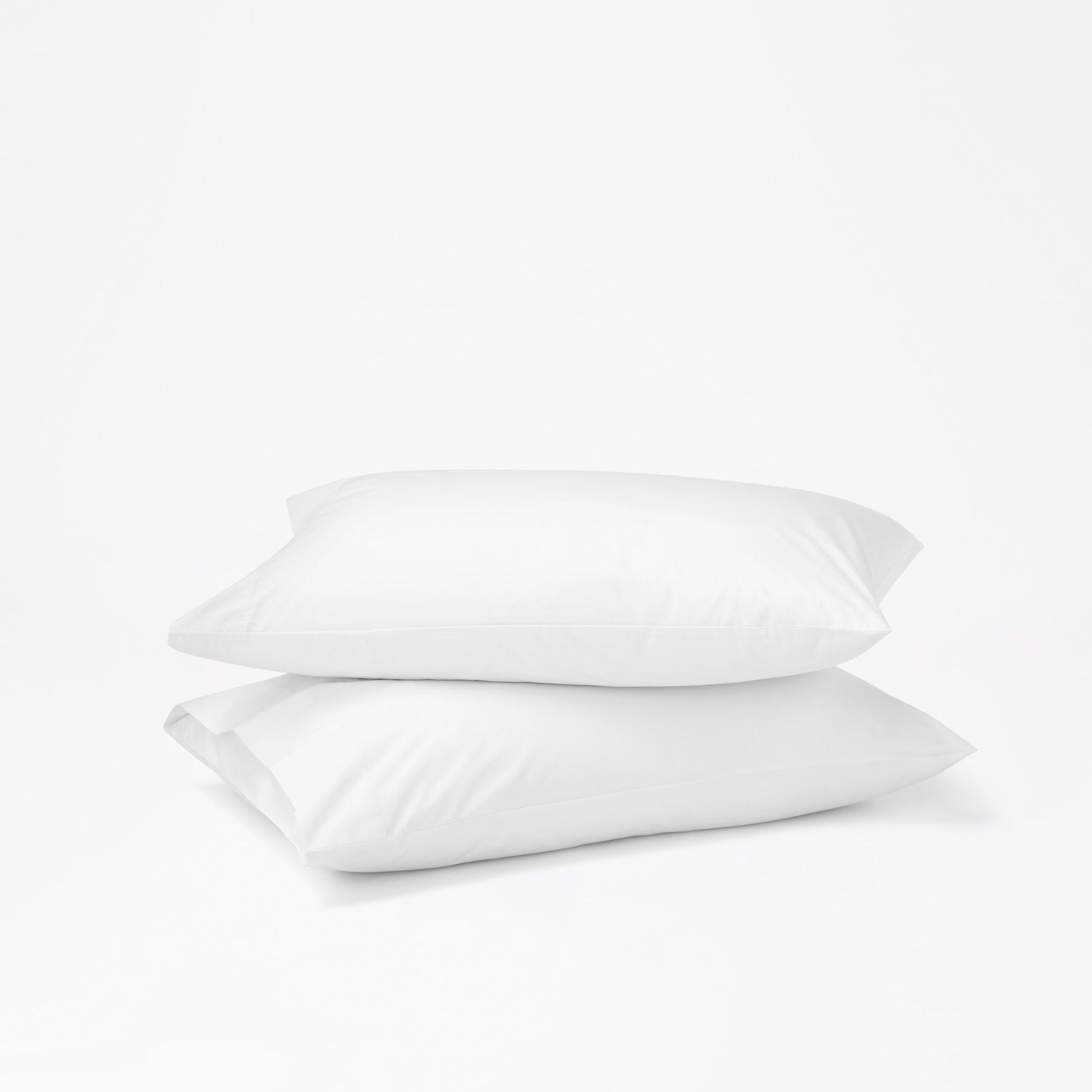 The Tuft and Needle Percale Pillowcase Set on two stacked pillows||color:cloud