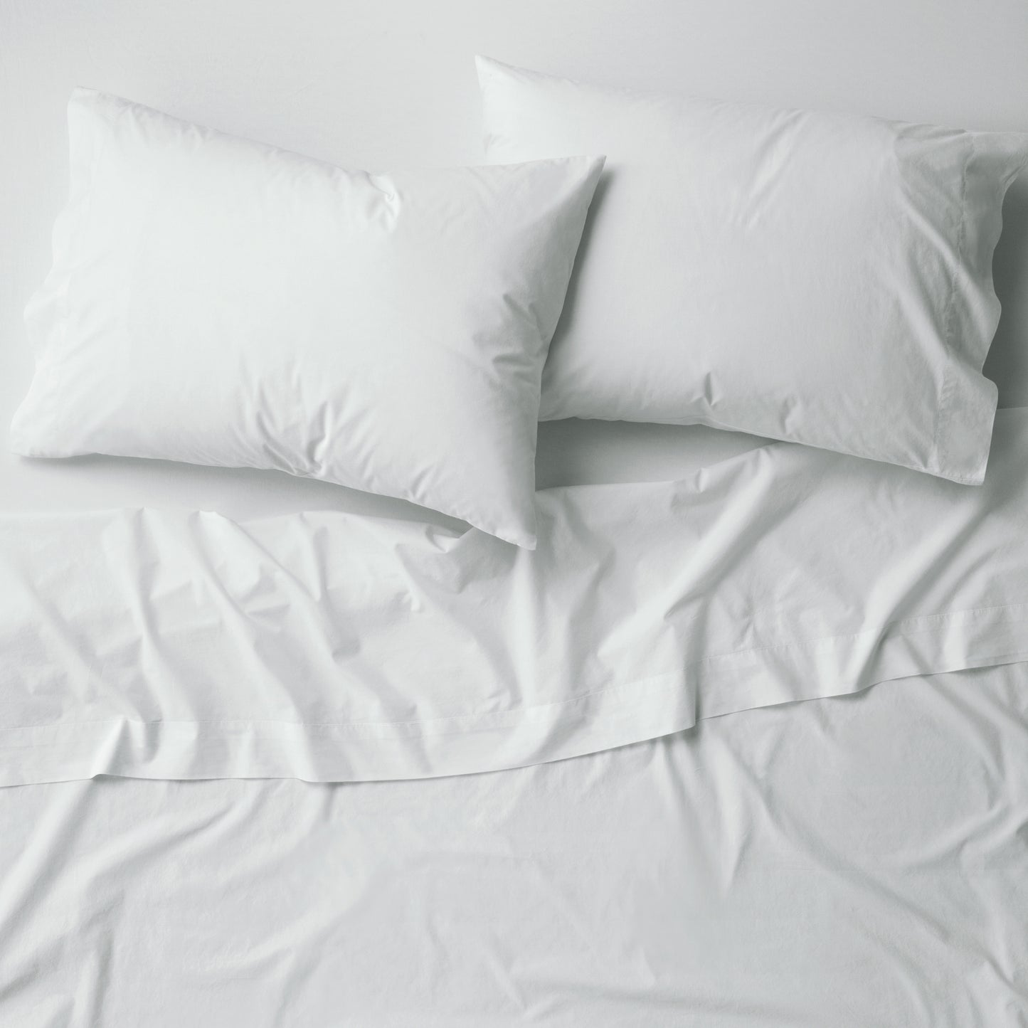 The Tuft and Needle Percale Pillowcase Set on a mattress||color:glacier