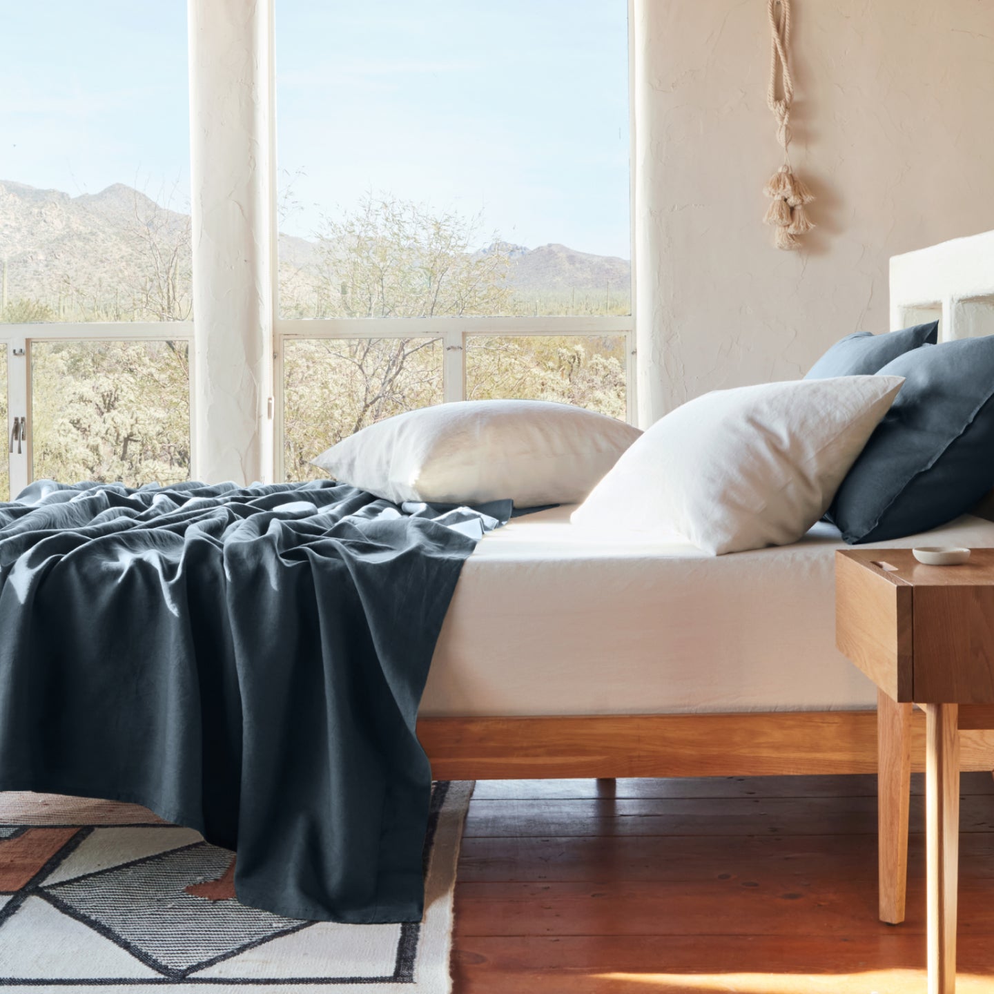 Linen sheet set draped on a Tuft and needle mattress with 4 pillows on top, blue and red.