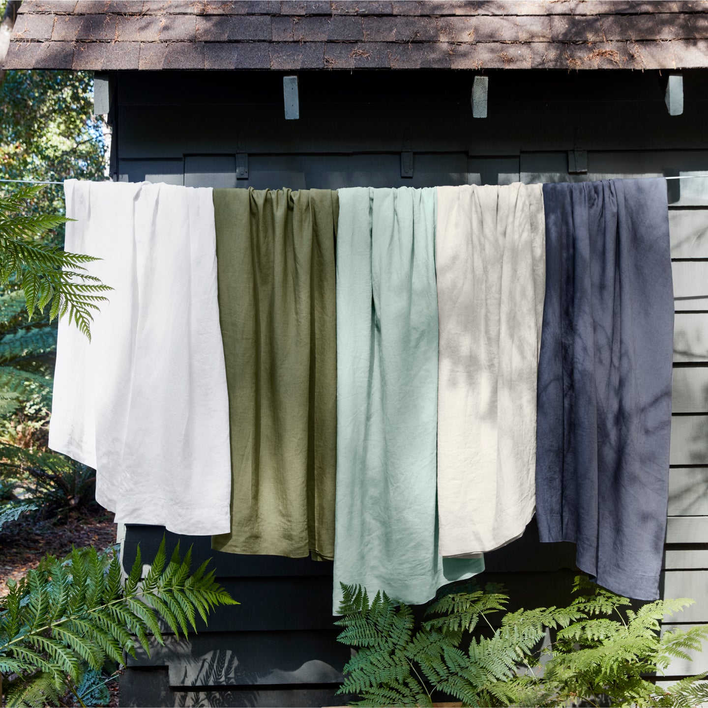 5 different colored linen sheets hanging on a clothes line outside