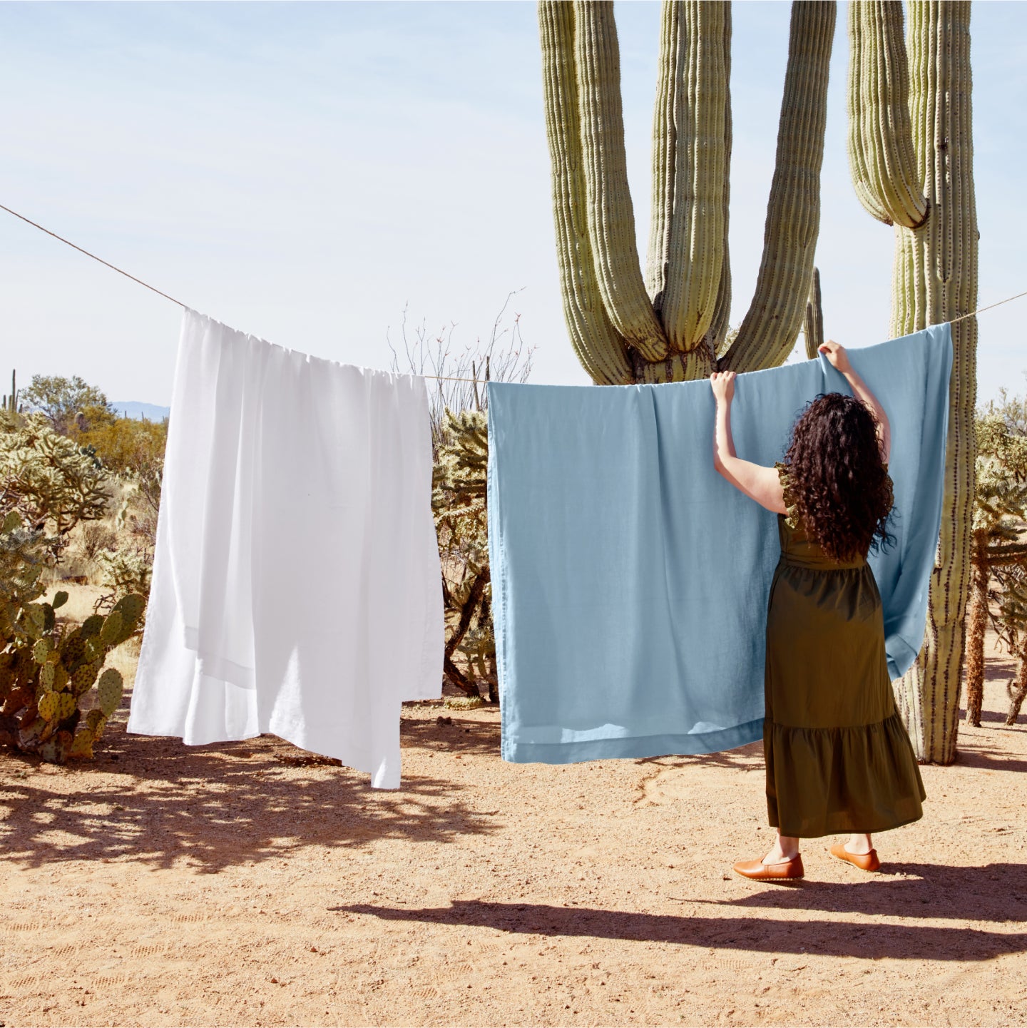 Woman hanging up sheets on clothes line