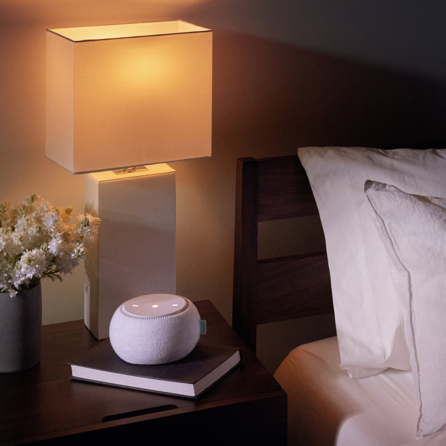 The Tuft and Needle White Noise Machine next to a mattress in a bedroom