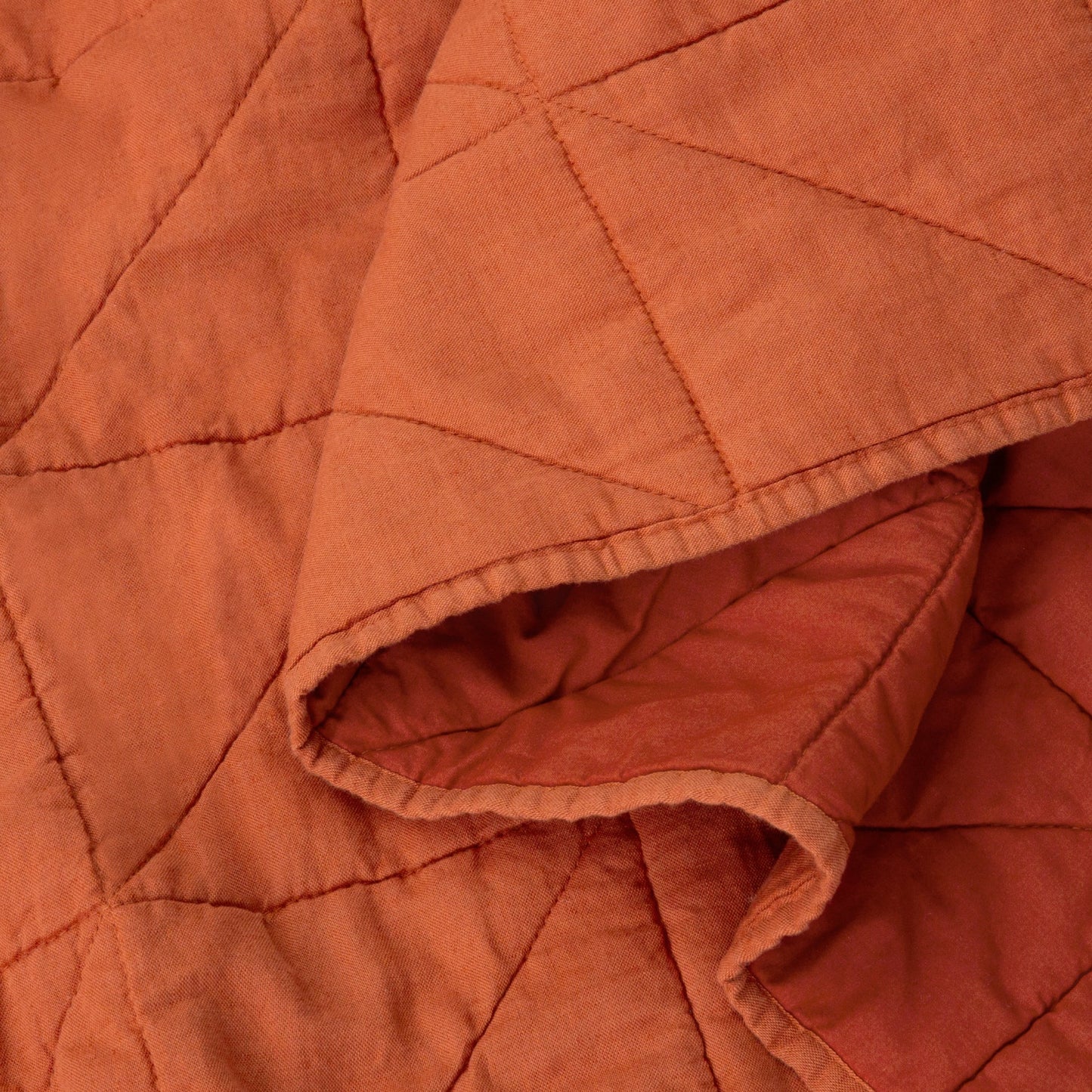 Close-up view of the fabric on the Tuft and Needle Quilt color cayenne