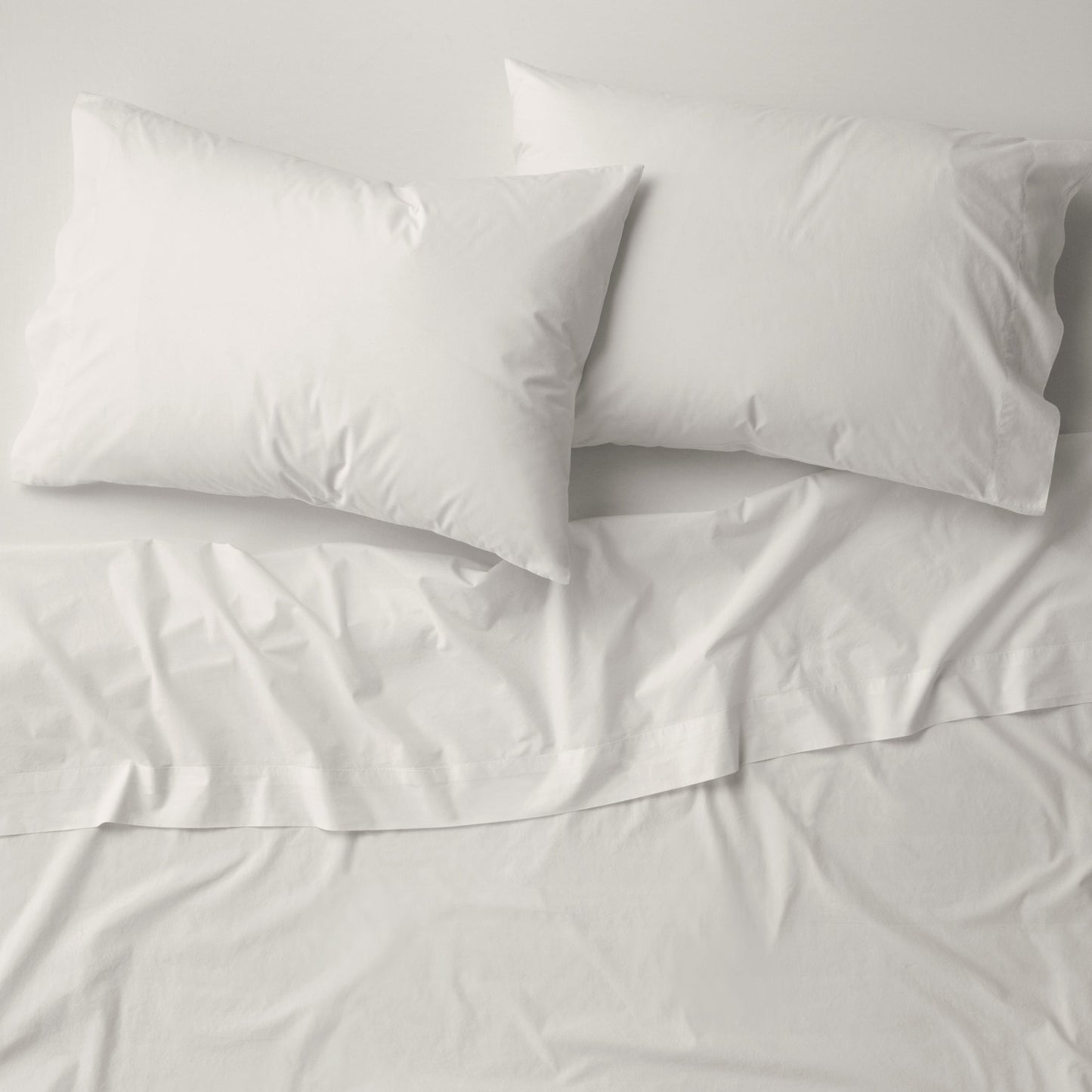 The Tuft and Needle Percale Pillowcase Set on a mattress||color:sand
