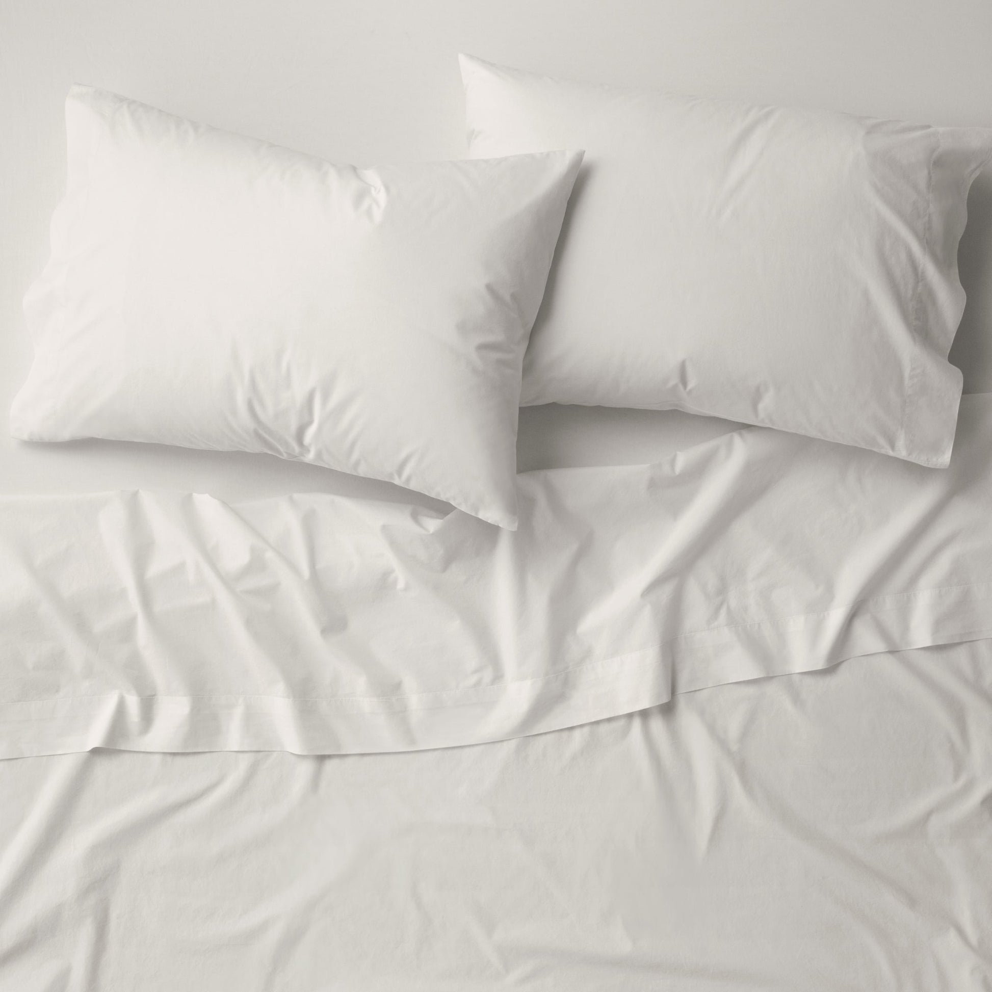 The Tuft and Needle Percale Pillowcase Set on a mattress||color:sand