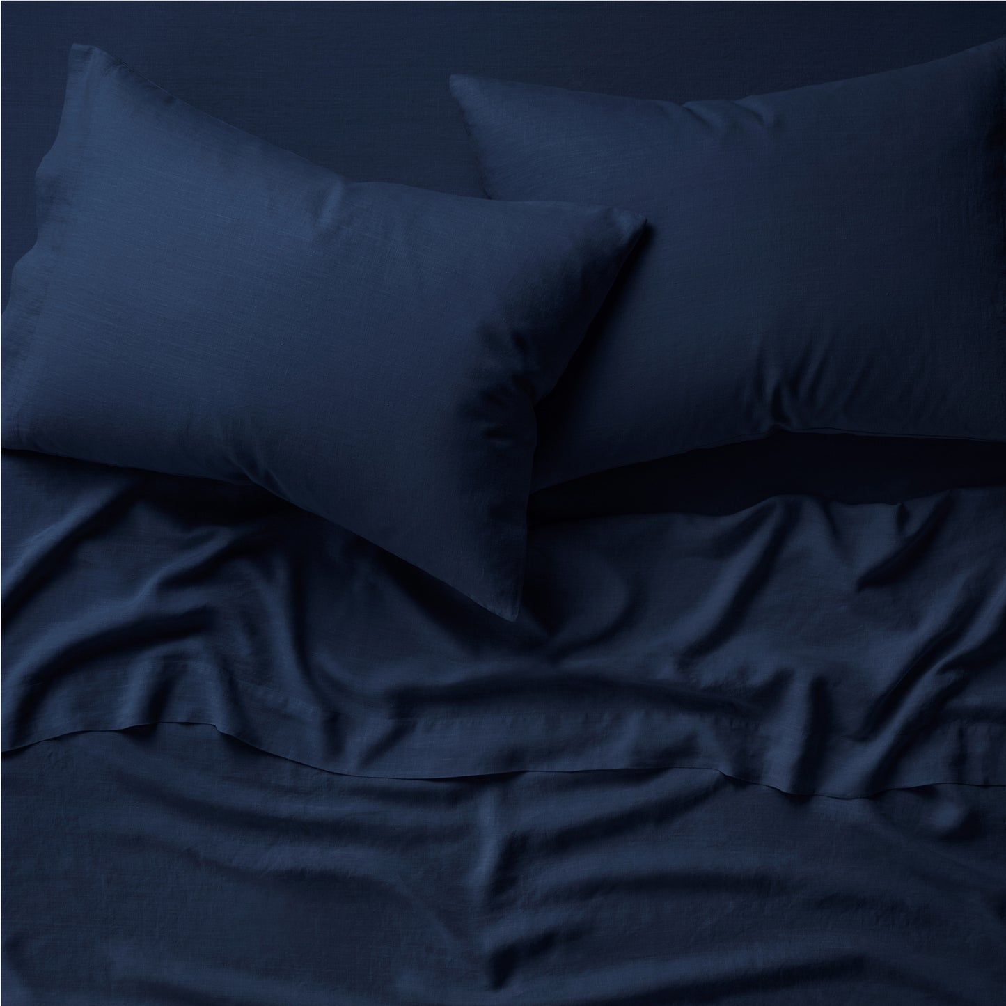 Two pillows on a bed dressed in the Tuft and Needle Hemp Pillowcase Set||color:midnight
