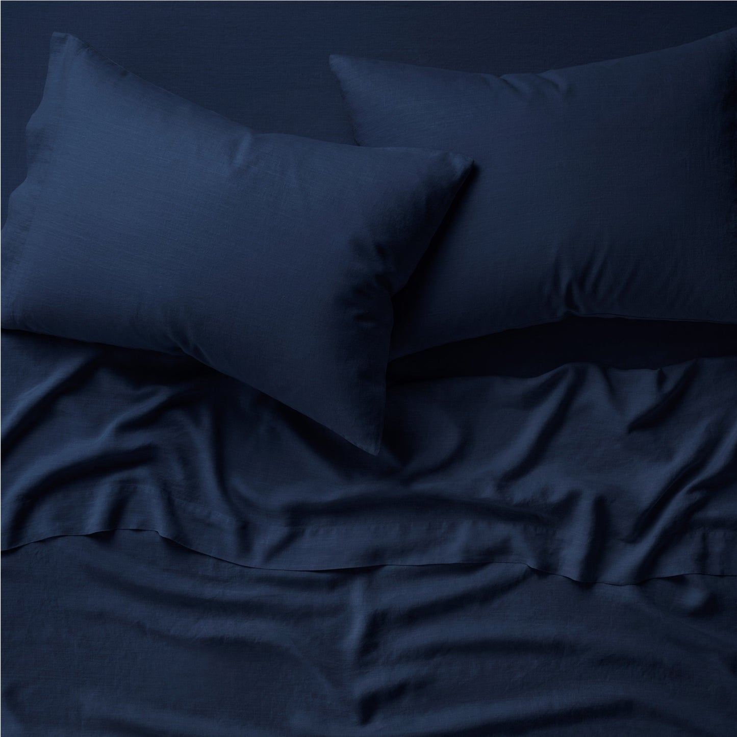 Two pillows on a bed dressed in the Tuft and Needle Hemp Pillowcase Set||color:midnight
