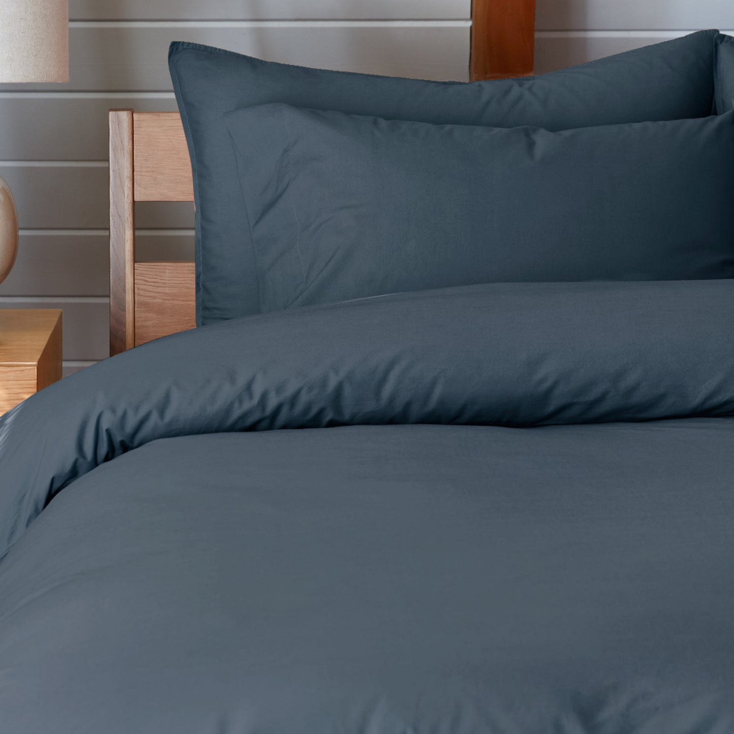 The Tuft and Needle Percale Pillowcase Set on a mattress in a bedroom||color:slate