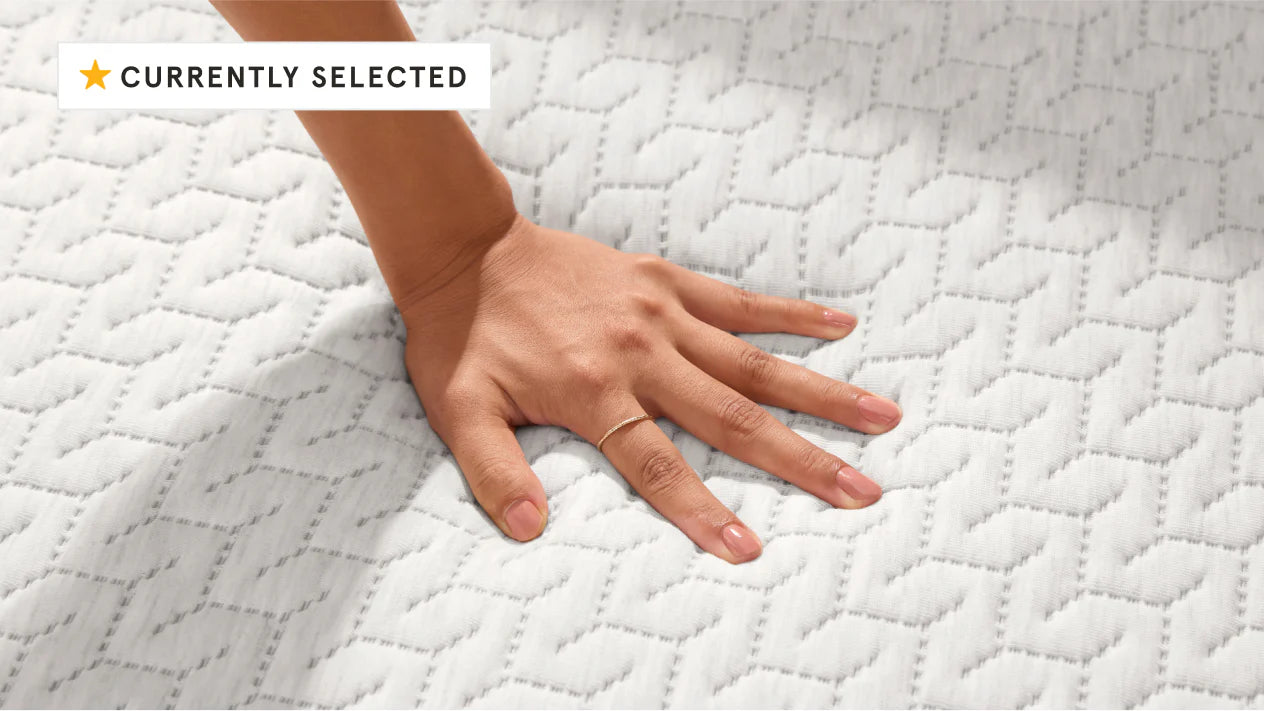 Woman's hand pressing down on the top of a foam mattress