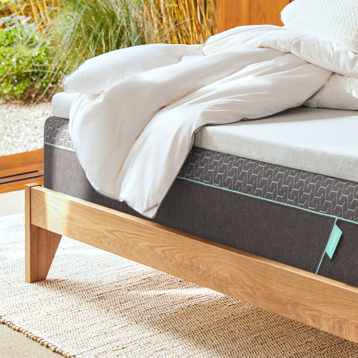 Tuft and Mattress on a wooden bed frame with white bedding outdoorseedle