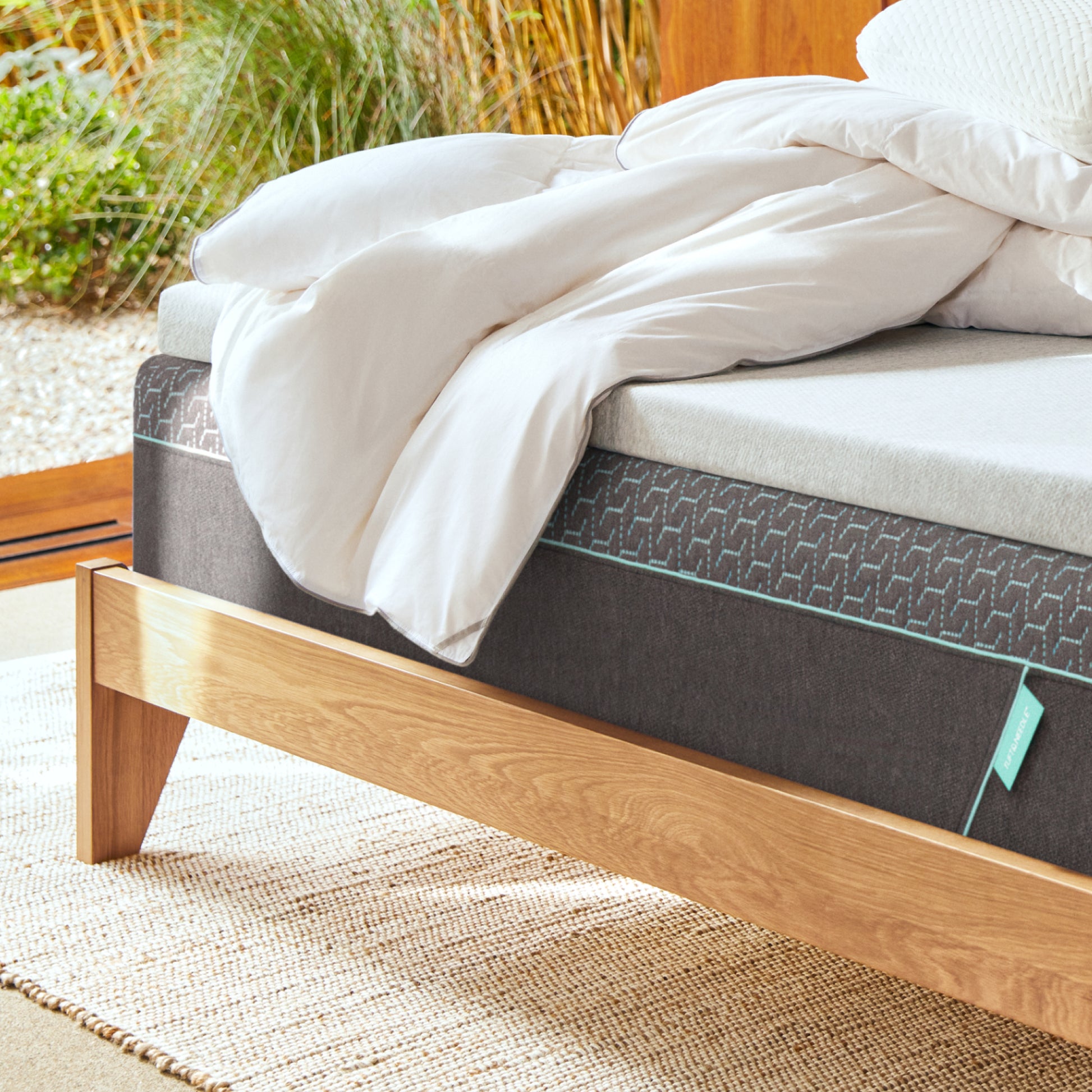 Tuft and Mattress on a wooden bed frame with white bedding outdoorseedle