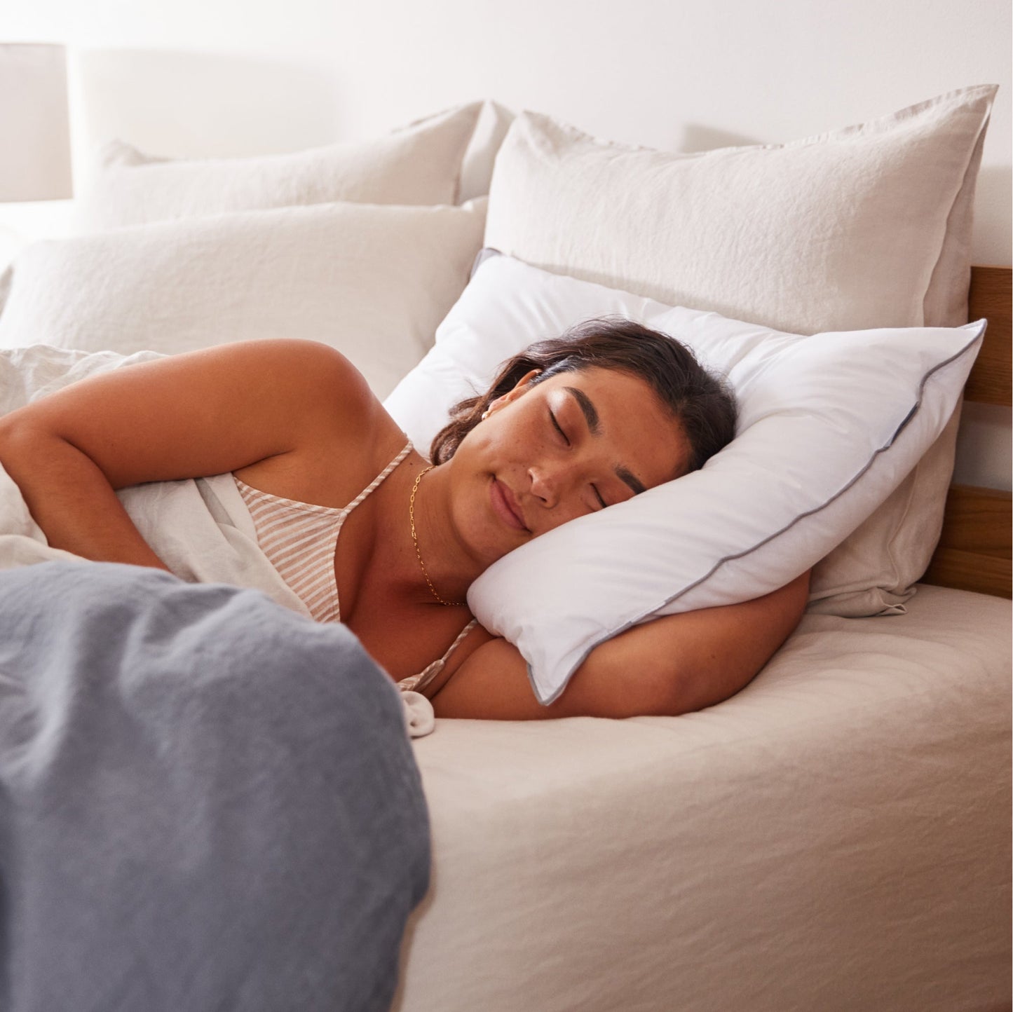 Woman laying asleep on her left side with her head on a Tuft and needle down alternative pillow