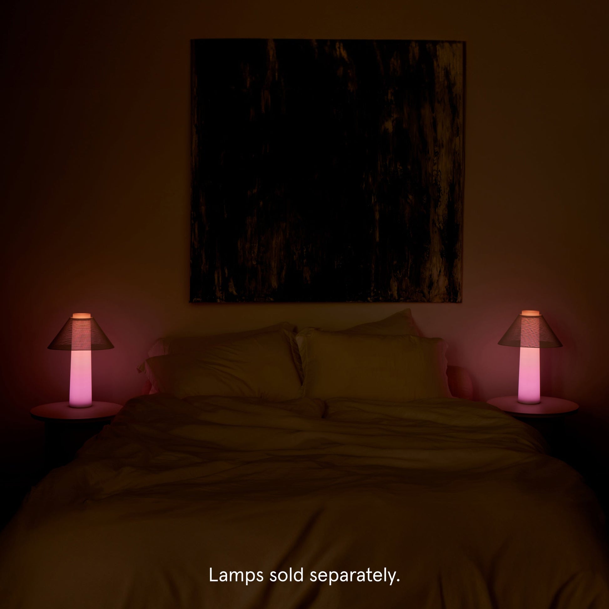 Tuft and Needle mattress with 2 Loftie Lamp on both sides on the bed on end tables. Both lamps are illuminated pink with the room lights out