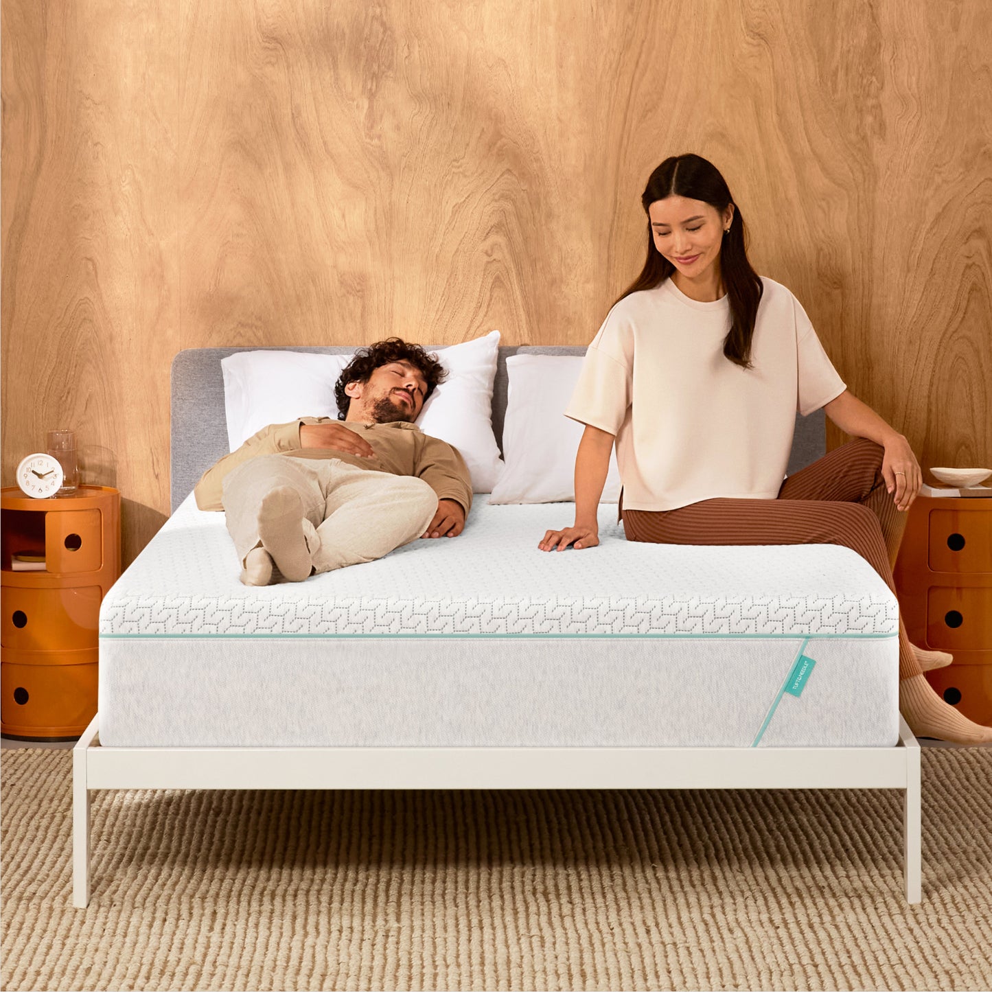 Man and woman laying on a Tuft & Needle Original Hybrid mattress sitting in a white bedframe