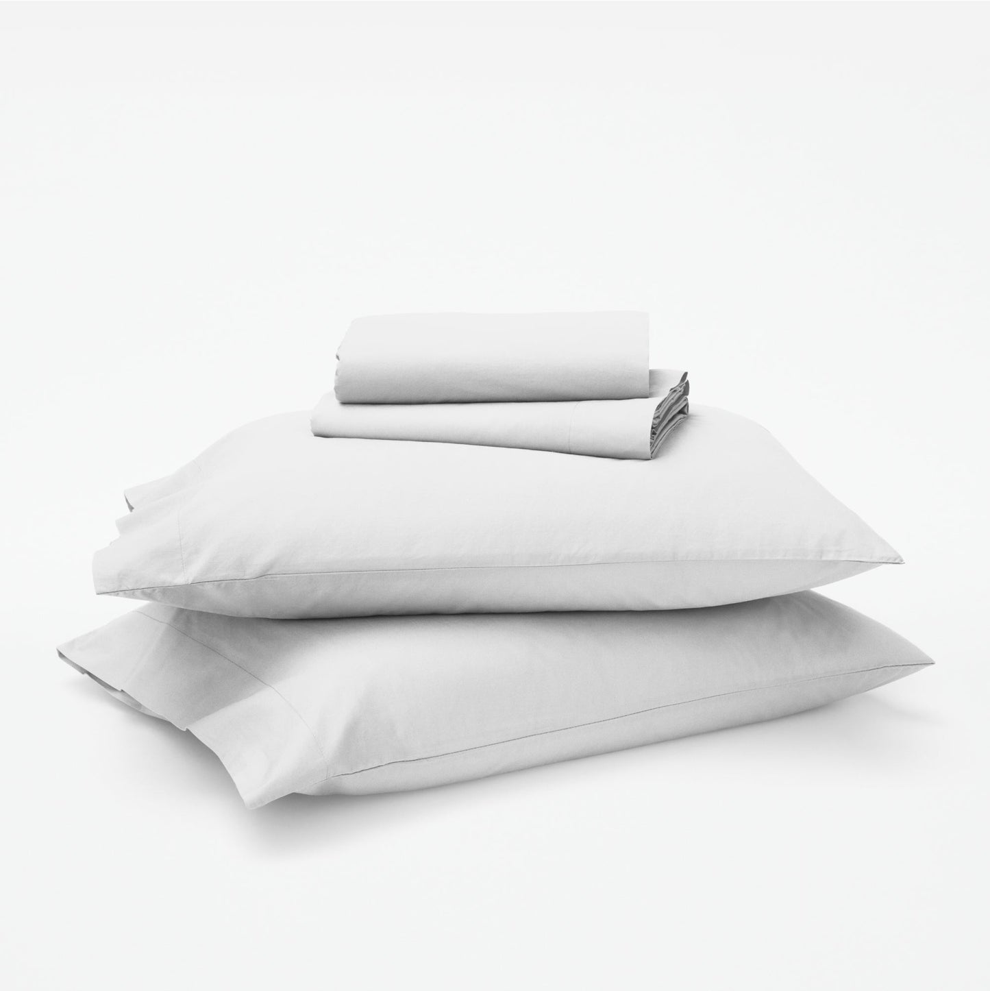 The Tuft and Needle Classic Percale Sheet Set, 1 sheet and pillowcases stacked on top of 2 pillows || color: Cloud
