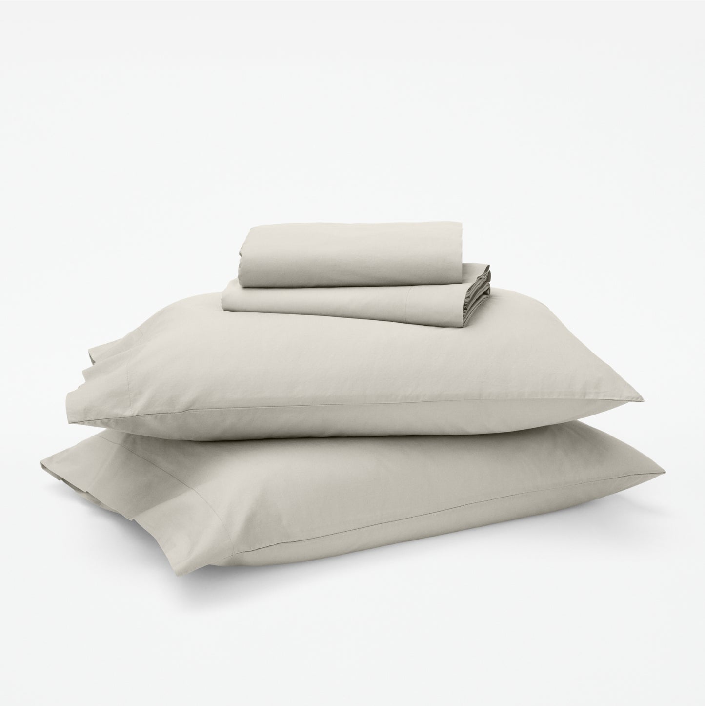 The Tuft and Needle Classic Percale Sheet Set, 1 sheet and pillowcases stacked on top of 2 pillows || color: Sand