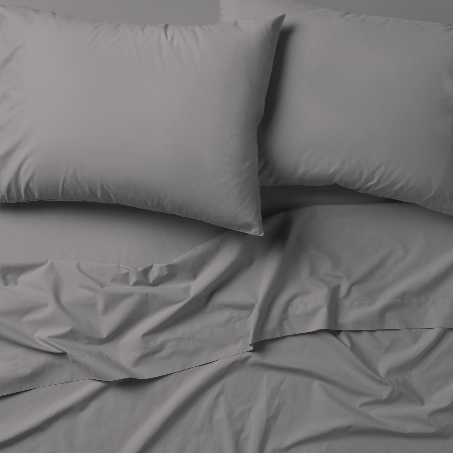 The Tuft and Needle Classic Percale Sheet Set, 2 pillows on top of a sheet on a mattress || color: Gray Quill