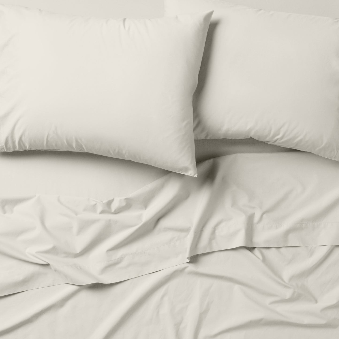 The Tuft and Needle Classic Percale Sheet Set, 2 pillows on top of a sheet on a mattress || color: Sage