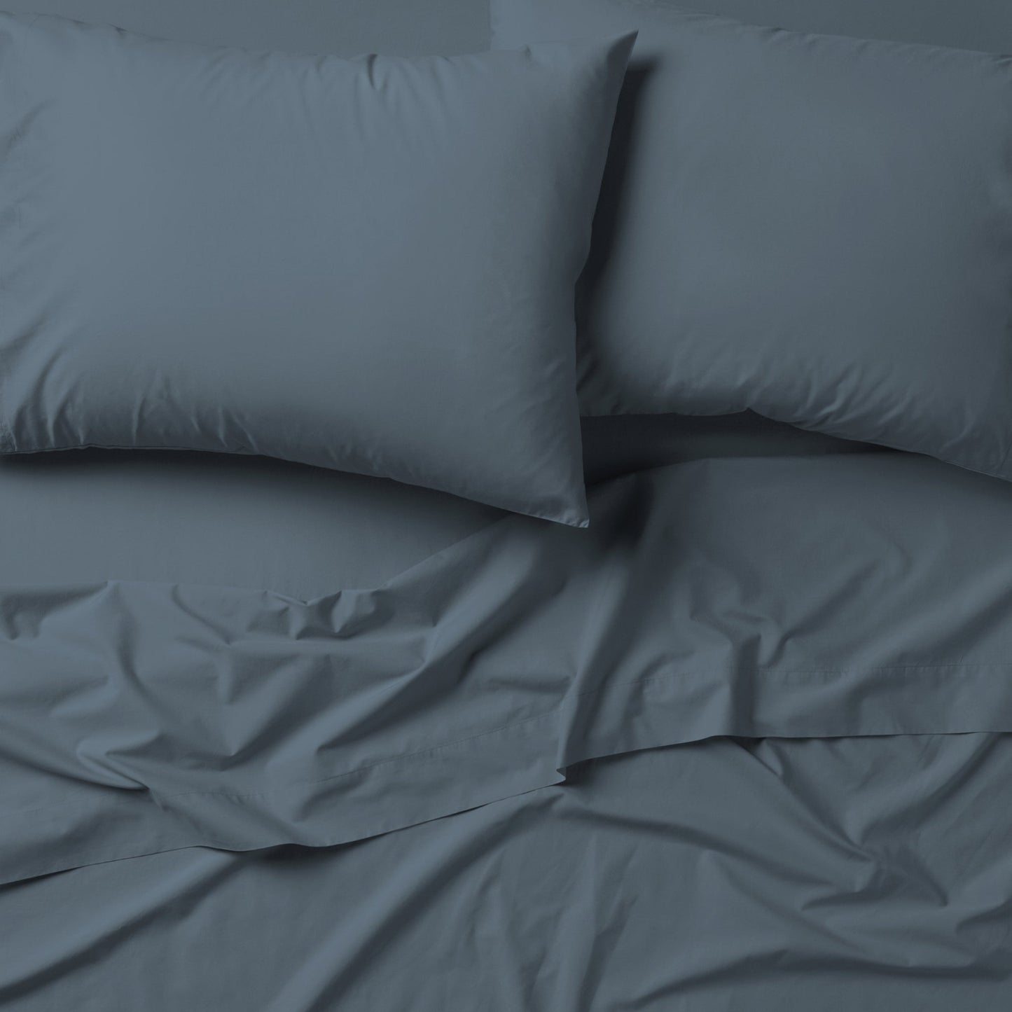 The Tuft and Needle Classic Percale Sheet Set, 2 pillows on top of a sheet on a mattress || color: Slate