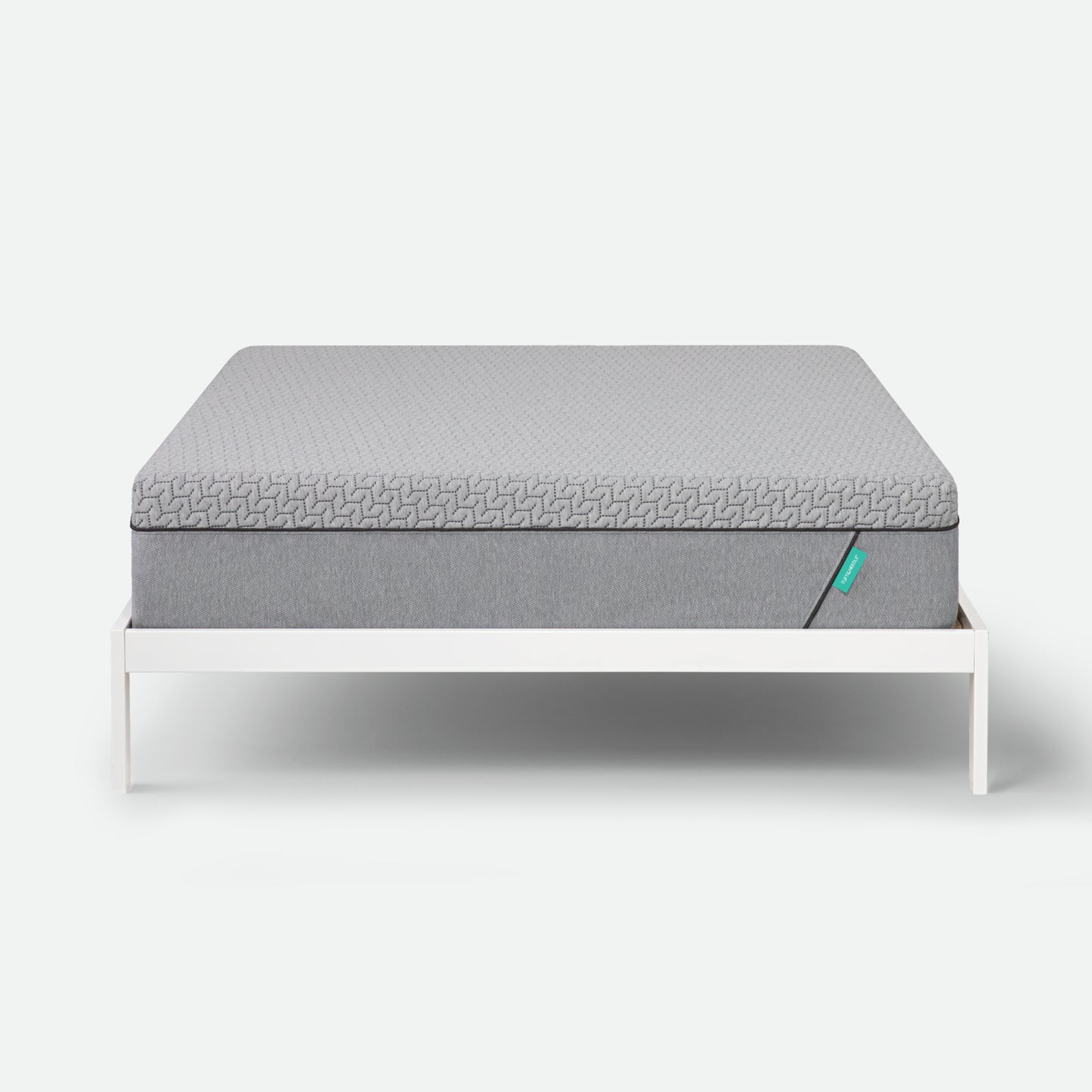 Tuft & Needle Gray mattress on a white bed frame against a white background