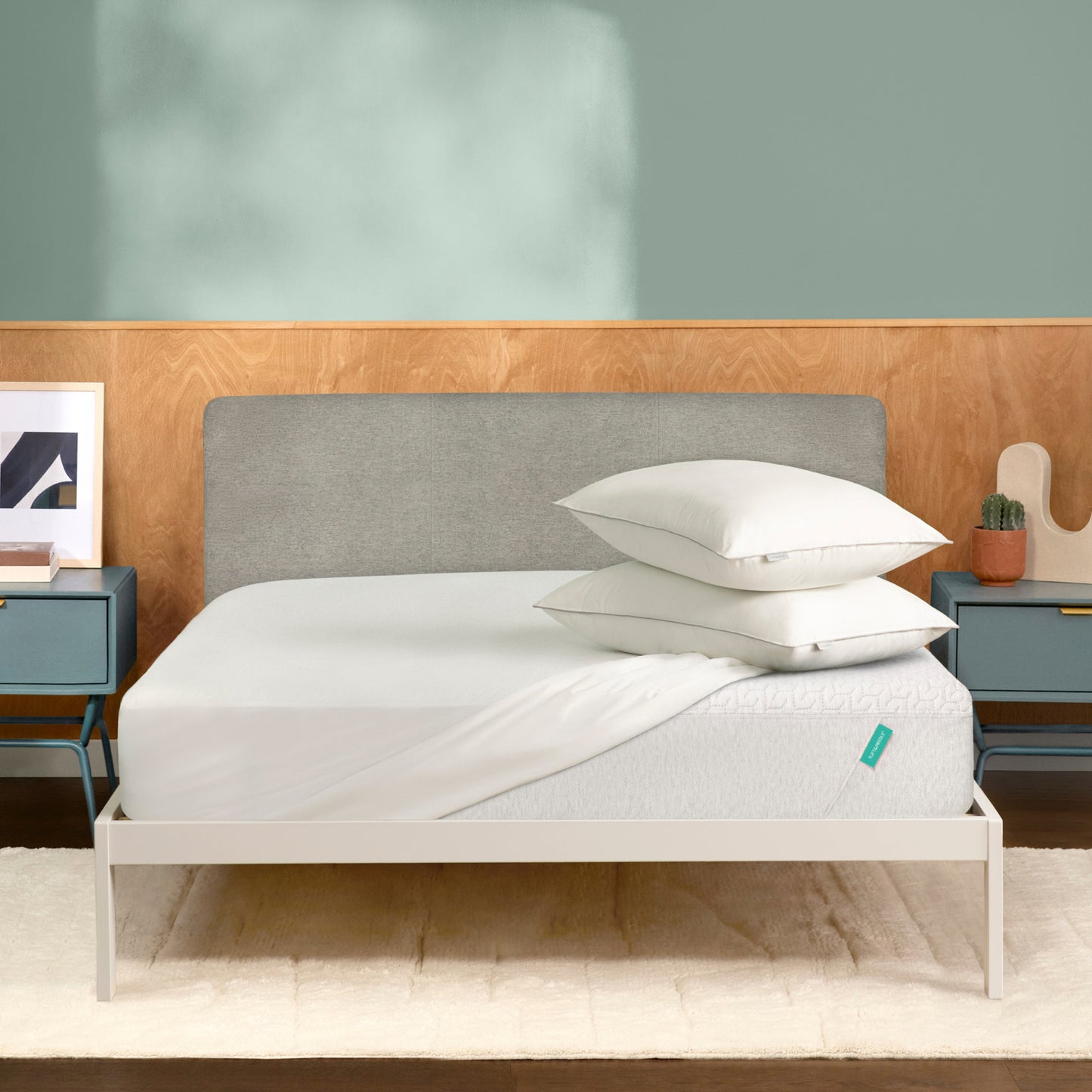 Tuft & Needle Bed with white bedding and gray headboard against a light green wall.