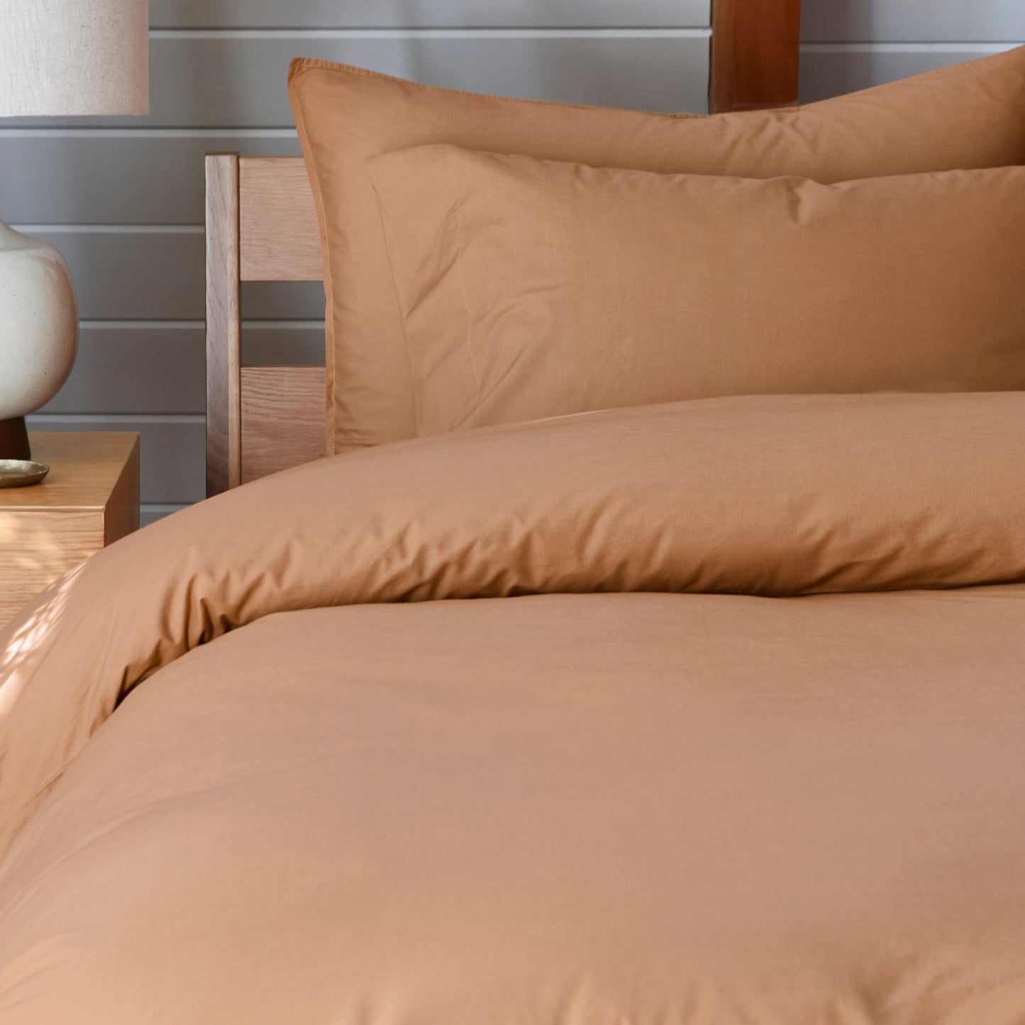 The Tuft and Needle Percale Pillowcase Set on a mattress in a bedroom||color:canyon