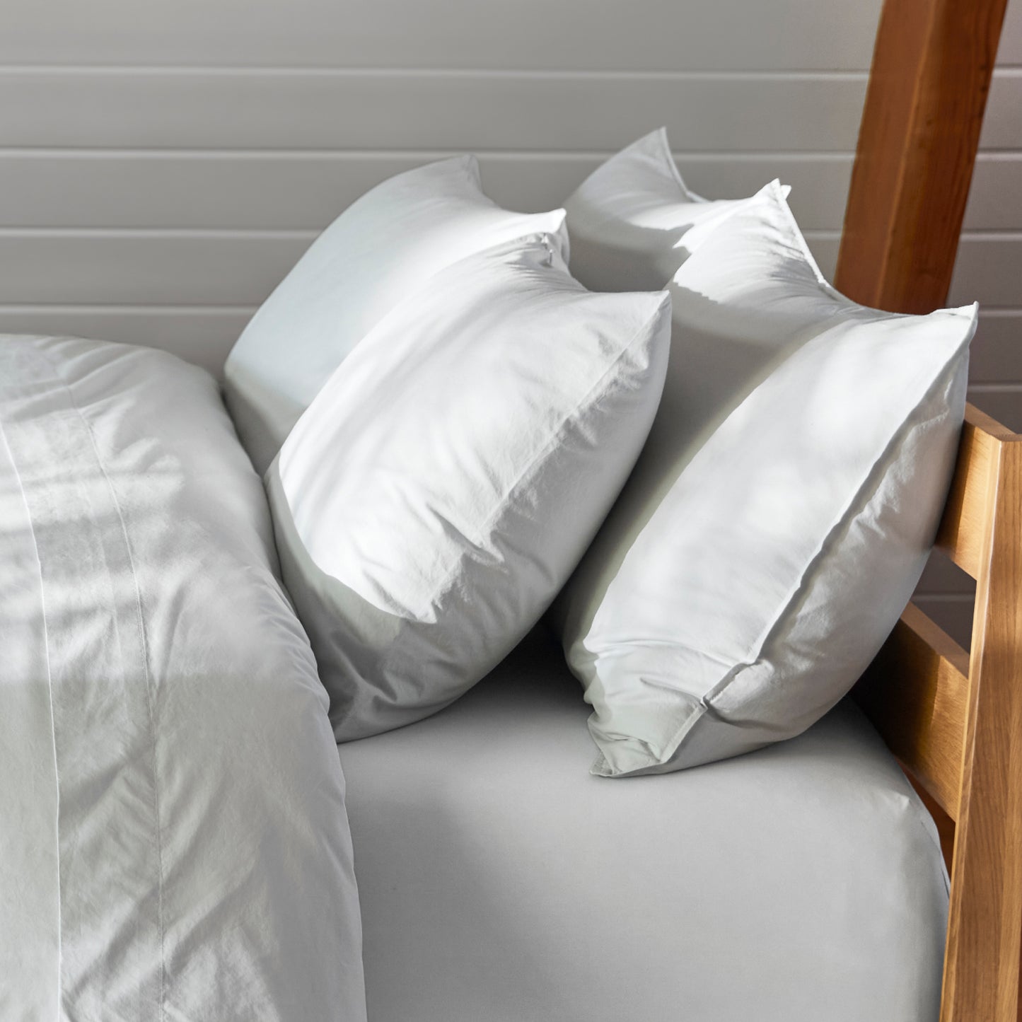 The Tuft and Needle Percale Pillowcase Set on a mattress in a bedroom||color:glacier
