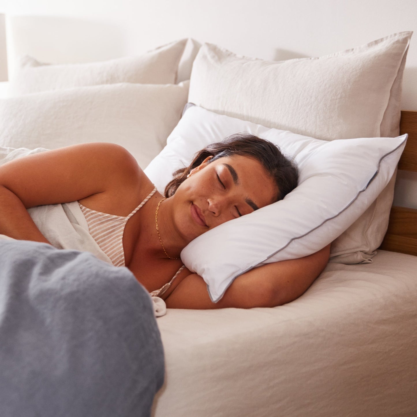 A woman sleeping in bed on the Tuft and Needle Down Alternative Pillow Set