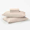 The Tuft and Needle Organic Jersey Sheets folded and stacked on 2 pillows||color:oatmeal