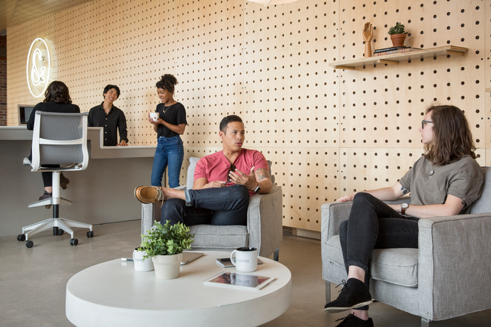 Customers talking to each other while sitting down at a table inside a Tuft & Needle Retail Mattress Store