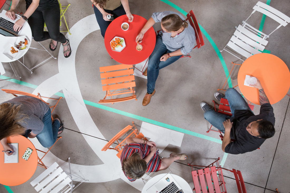 Arial picture of people having coffee and brightly colored round tables and chairs