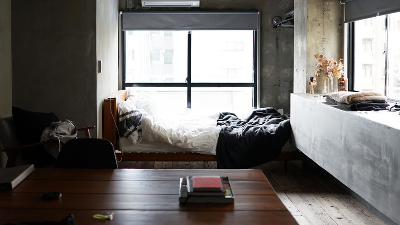 Picture of a bed with white and grey bedding sitting directly in front of a big window