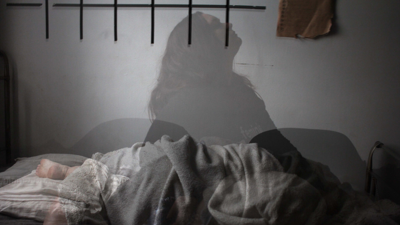 Depicting a woman not being able to sleep but is laying down under blankets