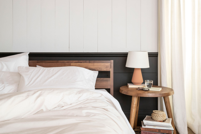 Tuft & Needle mattress, wood bed frame and end table in a bedroom with white and black walls