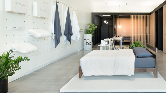 Picture of the inside of the Kansas City Tuft & Needle Store with Pillows & Sheets hung on the wall and a T&N Mattress set up on the floor