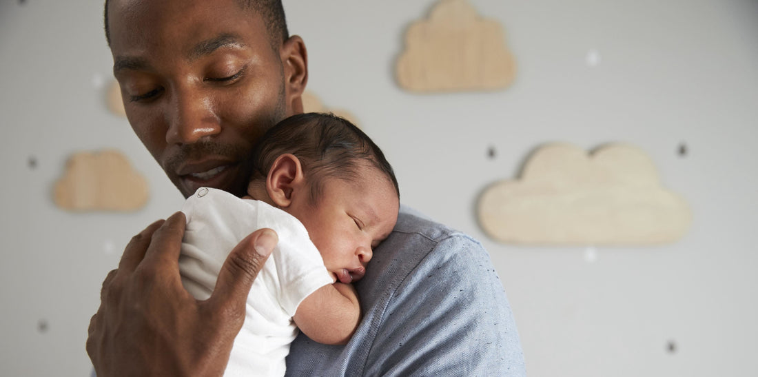 Picture of a dad holding his sleeping baby on his shoulder