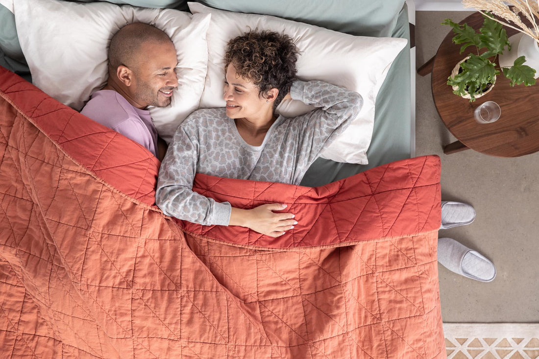 Man and woman laying in bed smiling at each other
