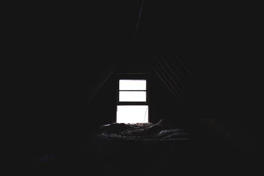 Dark room with an undressed window open and a bed in front of it