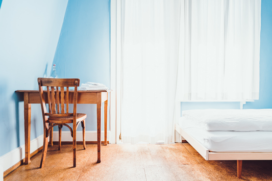Light blue bedroom with a simple wood desk and bed in it