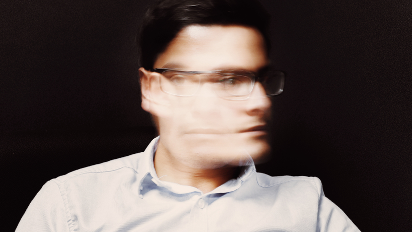 Man with glasses shaking his head side to side like saying no